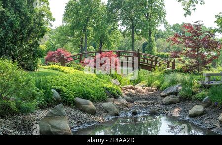 Un magnifique pont voûté traverse une petite rivière dans cette joli parc printanier Banque D'Images