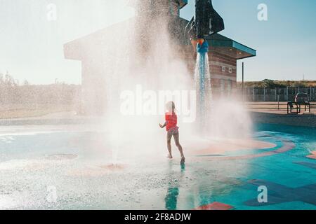 Mignon adorable caucasien drôle fille jouant sur le terrain de jeu de bloc d'eau le jour d'été. Enfant heureux s'amuser dans l'eau. Sports nautiques saisonniers Banque D'Images