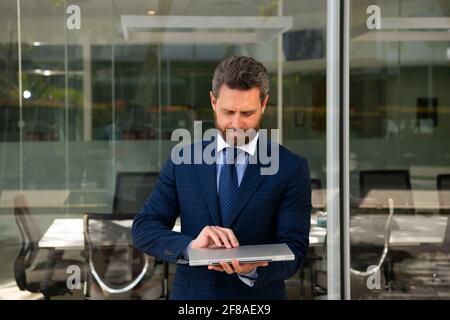 Homme d'affaires à l'extérieur. Beau homme d'affaires habilement habillé debout à l'extérieur dans la rue du bureau. Banque D'Images