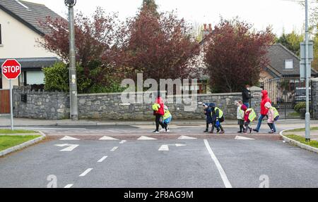 Dublin. 13 avril 2021. Les élèves marchent devant une école rouverte à Dublin, Irlande, le 12 avril 2021. L'Irlande a commencé lundi à assouplir certaines de ses restrictions COVID-19 comme prévu. Les gens sont autorisés à voyager librement dans le comté où ils vivent ou à moins de 20 kilomètres de leur maison, avec des rassemblements en plein air autorisés pour pas plus de deux ménages, l'éducation en classe pour tous les élèves du primaire et du secondaire a repris, et tous les projets de construction résidentielle ont rouvert. Credit: Xinhua/Alay Live News Banque D'Images