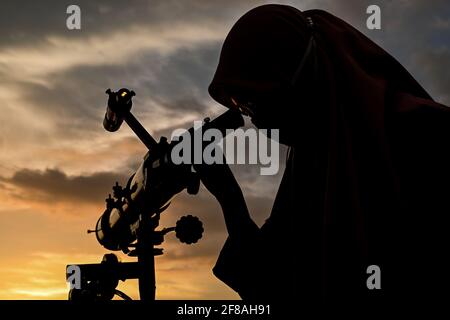 Makassar, Indonésie. 12 avril 2021. Une femme, à travers un télescope, observe la nouvelle lune qui signale le début du mois de jeûne du Ramadan, à Makassar, Sulawesi du Sud, Indonésie, avril 12, 2021. Credit: Niaz Sharief/Xinhua/Alay Live News Banque D'Images