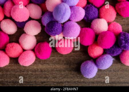 Boules de pompons molletonnées rondes roses et violettes sur fond de bois. Bouquet de pompons Banque D'Images
