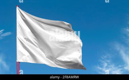 Nettoyez le drapeau blanc vierge sur le mât contre le ciel bleu, comme arrière-plan du texte Banque D'Images