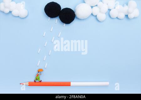 Figurine Clown marchant sur un crayon coloré sous la pluie isolée sur fond bleu Banque D'Images