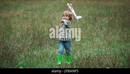 Enfant garçon jouant avec l'avion jouet. Souvenirs d'enfance ou imagination de rêve concept. L'aviateur de pilote d'enfant avec avion joue sur la nature estivale. Garçon avec Banque D'Images