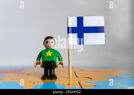 POZNAN, POLOGNE - 06 avril 2021 : figurine jouet joutive située à côté d'un drapeau national finlandais. Banque D'Images