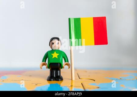 POZNAN, POLOGNE - 06 avril 2021 : figurine jouet joutive située à côté d'un drapeau national du Mali. Banque D'Images