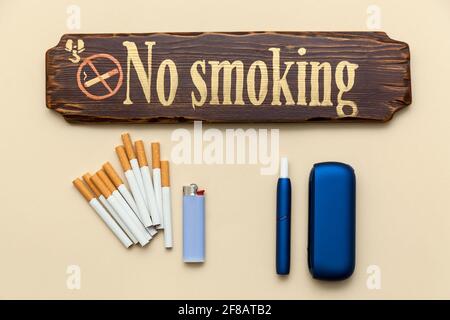 Cigarette électronique bleue IQOS, cigarettes ordinaires avec un briquet et inscription ne pas fumer sur fond beige. Photo avec place pour votre texte, Banque D'Images