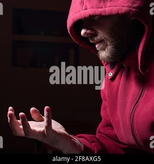 Homme barbu suspect dans un capot dans l'obscurité Banque D'Images