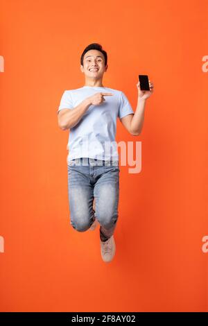 Homme d'affaires asiatique sautant et tenant un smartphone Banque D'Images