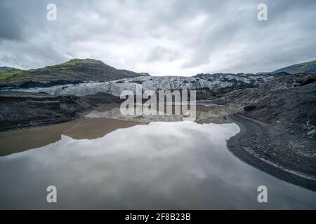 Longue exposition du glacier islandais par le lagon du glacier par temps froid et nuageux. Glacier se réfléchit dans l'eau. Fjallsarlon, Islande. Banque D'Images