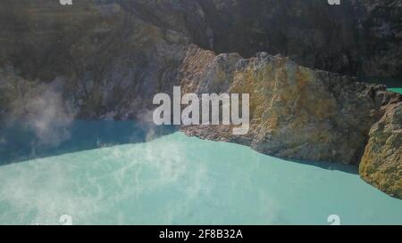 Vol au-dessus des lacs de Vulanice à basse altitude. Vue rapprochée d'un mur de roche séparant les lacs colorés. Cratère volcanique de trois couleurs Kelimutu couvert Banque D'Images