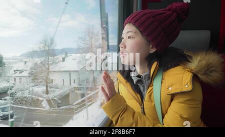 Portrait de style de vie d'une jeune femme japonaise asiatique heureuse et belle dans une veste et un chapeau jaunes regardant à travers la fenêtre du train en voyage pendant les vacances d'hiver Banque D'Images