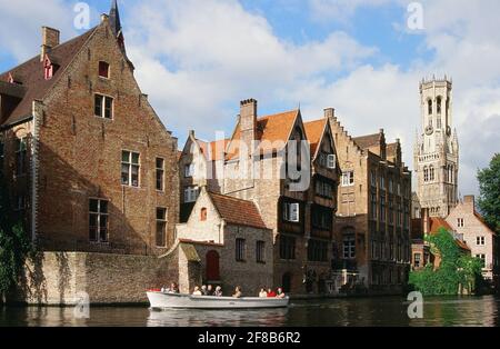 Bâtiments historiques à la Rozenhoedkaai à Bruges, Belgique, avec un bateau et le beffroi en arrière-plan Banque D'Images