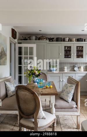 Cuisine de style Shaker avec bancs Gustavian et sol travertin dans les années 1930 West Sussex rénovation côtière.