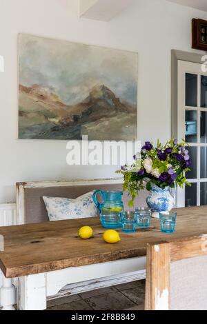 Œuvre de Sue Green au-dessus de la table avec des bancs Gustavian dans West Sussex cuisine repensée. Banque D'Images