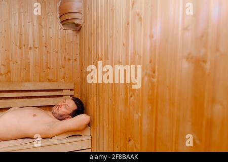 beau homme d'âge moyen allongé dans un sauna électrique dans un hammam, sauna avec vue rapprochée. concept détente et repos, espace copie Banque D'Images