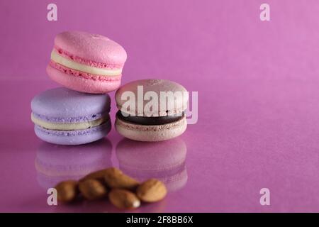 La cuisine macaron se traduit par un dessert Fratsuz et des noix d'amande sur fond rose avec un endroit pour le texte et le copyspace. Banque D'Images