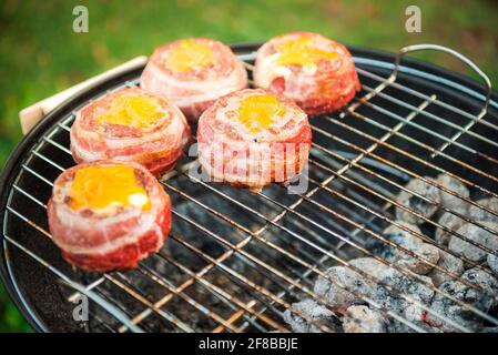 Faire de la bière fait maison peut Bacon les galettes sur le barbecue. Préparer les galettes farcies, enrobé de bacon et les grillades sur la chaleur indirecte dans la nature à bac Banque D'Images