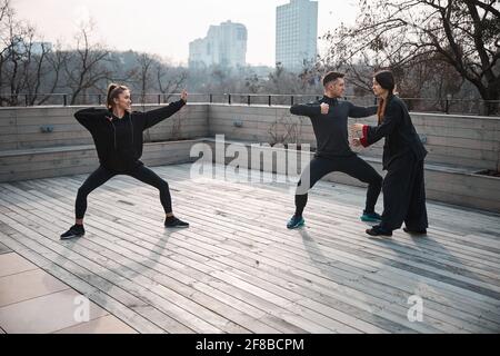 Les athlètes pratiquant le wushu posent avec un professeur les corrigeant Banque D'Images