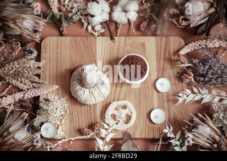 Composition avec fleurs sauvages séchées et produits de soin du corps sur un élément en bois au centre. Banque D'Images