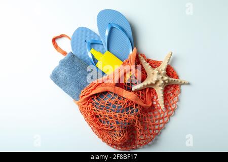 Sac avec crème solaire, tongs, serviette et étoiles de mer sur fond blanc Banque D'Images