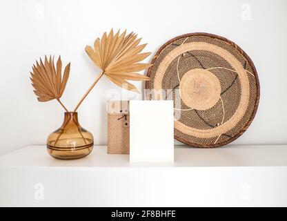 Feuille vierge de papier blanc non couché et enveloppe marron à un vase en verre avec des feuilles de palmier séchées Banque D'Images