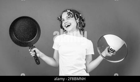 juste inspiré. petite femme tient la poêle. cuisine dans la cuisine. concept de la maison. cuisine pour enfants à la maison. enfance heureuse. enfant joyeux avec des pillards Banque D'Images