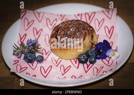 Roulé à la cannelle sur une assiette de bleuets et de fleurs Banque D'Images