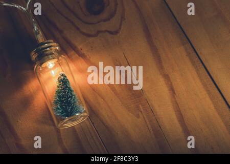 Ampoule et petit sapin de Noël dans un pot en verre arrière-plan en bois Banque D'Images