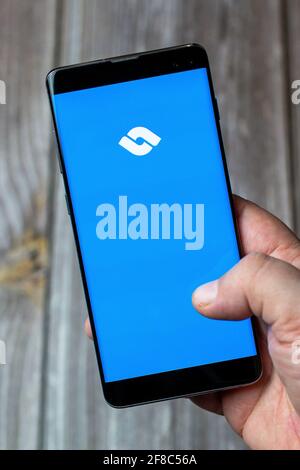 Un téléphone mobile ou mobile tenu dans un Main avec l'application d'échange de billet ouverte à l'écran Banque D'Images