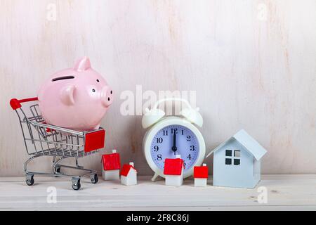 Porcins, chariots et petites maisons sur le fond de l'horloge. Le temps d'économiser pour l'immobilier. Banque D'Images