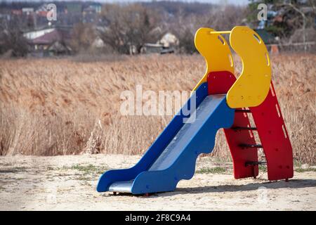 toboggan pour enfants situé dans un endroit déserté. pelouse séchée. aire de jeux vide. journée ensoleillée. Banque D'Images