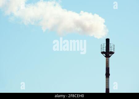 De la fumée s'échappe du tuyau de la chaufferie à gaz contre le ciel bleu. Le problème de la pollution de l'environnement et des émissions de gaz dans l'atmosphère. Arrière-plan environnemental avec espace de copie. Banque D'Images