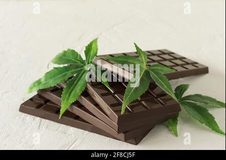 Feuilles de marijuana et chocolat noir sur fond de bois blanc. Banque D'Images