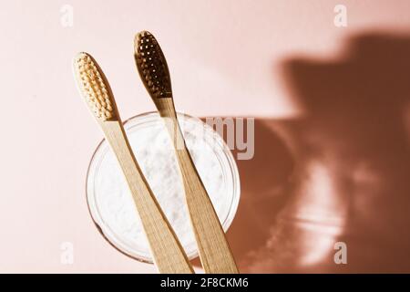 Deux brosses à dents en bambou et poudre de dent sur fond rose. Concept de produit écologique et biologique Banque D'Images