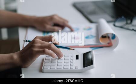 Gros plan homme d'affaires utilisant la calculatrice pour l'analyse de plan de fortune, comptable calculer rapport financier, ordinateur avec graphique. Affaires, Finances Banque D'Images