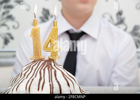 Bougies allumées sur le gâteau avec le numéro 14 Banque D'Images