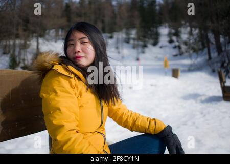 Portrait d'une jeune femme coréenne asiatique fraîche et attrayante veste d'hiver jaune souriante sur le banc au-dessus du lac gelé Dans la neige, moun dans les Alpes suisses Banque D'Images