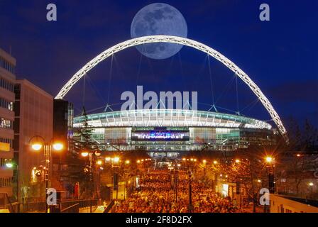 Une pleine lune derrière l'arche illuminée du stade Wembley à Londres, au Royaume-Uni Banque D'Images