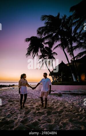 Coucher de soleil Aruba sur la plage de Divi, coucher de soleil coloré sur la plage d'Aruba. Couple hommes et femme asiatique de milieu d'âge et hommes européens en vacances Aruba Banque D'Images