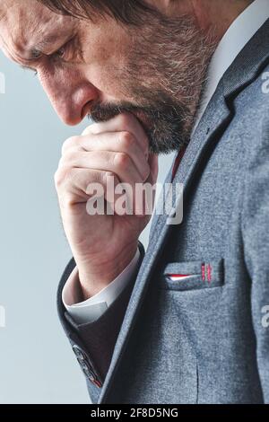 Homme d'affaires pensif surchargé de pensées pensant avec la main sur le menton, portrait sélectif de mise au point, image verticale Banque D'Images