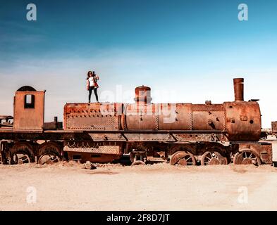 Fille sur un train à vapeur rouillé près d'Uyuni en Bolivie. Trains de cimetière. Banque D'Images