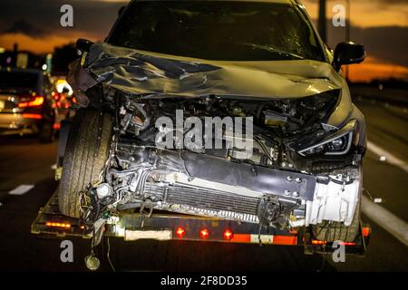 Chargé une voiture brisée sur un camion de remorquage après un accident la nuit Banque D'Images