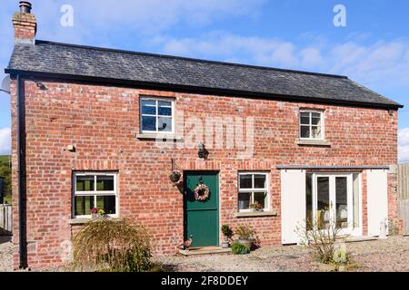 Jolie maison de grange irlandaise reconvertie avec porte stable et portes coulissantes de grange. Banque D'Images