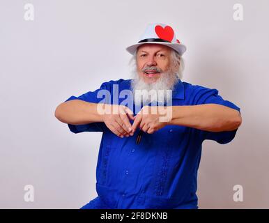 Joyeux vieil homme célébrant la Saint-Valentin en faisant un signe de coeur avec ses mains Banque D'Images