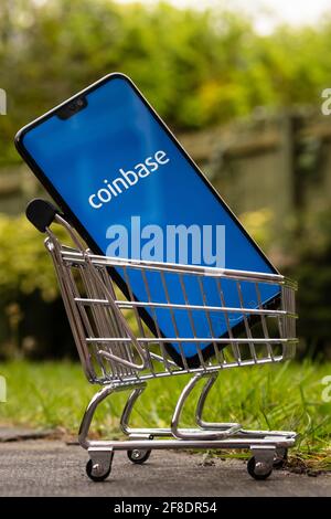 Concept de Coinbase IPO. Le logo de l'application Coinbase est visible sur l'écran du smartphone, qui est placé dans un chariot miniature. Stafford, Royaume-Uni, AP Banque D'Images