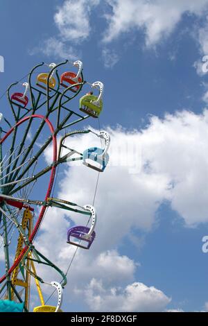 Une famille monte une grande roue dans un un skiy bleu et des nuages le jour de l'été Banque D'Images