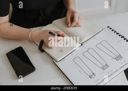 LEEDS, ROYAUME-UNI - 03 mars 2021 : une jeune femme d'affaires et designer de mode revoyant ses croquis de conception de vêtements. Banque D'Images