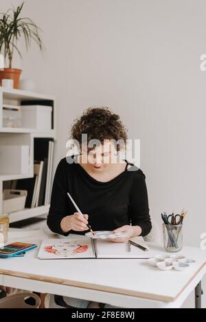 LEEDS, ROYAUME-UNI - 03 mars 2021 : artiste féminine travaillant sur un dessin coloré d'un portrait féminin dans un carnet d'esquisses. Banque D'Images